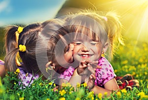 Happy girls twin sisters kissing and laughing in the summer