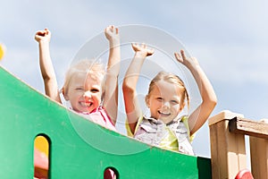 Happy girls waving hands on children playground