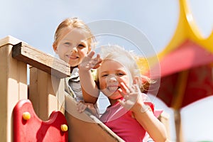 Happy girls waving hands on children playground