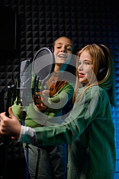 Happy girls wearing headphones singing in record studio