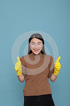 Happy glad and cheerful asian houseworker from chores thumbs up