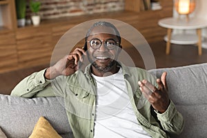 Happy glad mature black man in glasses calls by smartphone, talks, has good news at spare time