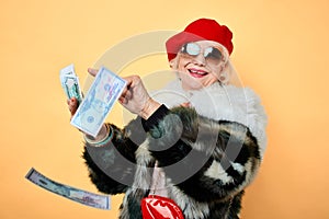 Happy glamour senior old lady throwing stack of dollar bills