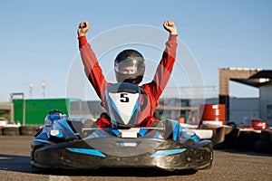 Happy go-cart driver raising hands up rejoicing and celebrating win