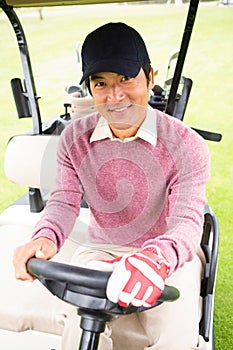 Happy golfer driving his golf buggy