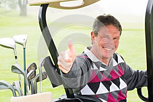 Happy golfer driving his golf buggy smiling at camera