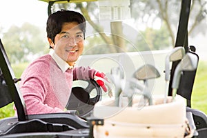 Happy golfer driving his golf buggy smiling at camera