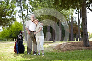 Happy Golfers. Full-length portrait of a happy senior couple standing with a bag of golf clubs on a golf course.