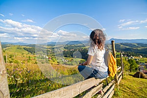 Happy gorgeous girl enjoy hills view sitting in flower field on the hill with breathtaking nature landscape