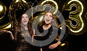 Happy gorgeous girls in stylish sexy party dresses holding gold 2023 balloons, having fun at New Year& x27;s Eve Party.