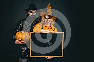 Happy gothic couple in Halloween costume. Jack-o-lanterns. Halloween poster or greeting card - people concept.