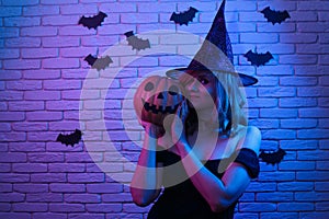 Happy gothic young woman in witch halloween costume and pumpkin