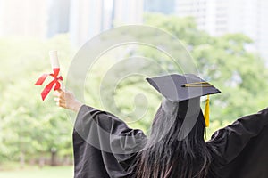 Happy graduate young Asian woman in cap and gown holding a certificated in hand, Education concept