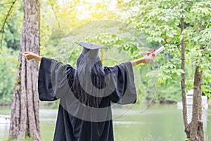 Happy graduate young Asian woman in cap and gown holding certificated in hand, Education concept