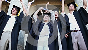 Happy graduated students raising their arms