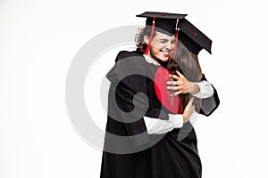 Happy graduated young students couple hugging  on white background