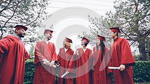 happy graduates laughing and celebrating graduation on college campus. Education, success and modern youth concept