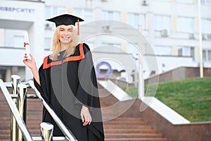 Happy graduation day for a young woman very beautiful with graduation cap smile large, while holding her diploma