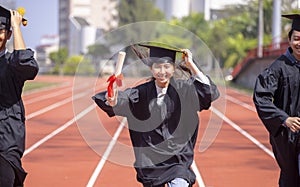 Happy graduation students  holding diploma and running on the stadium at school