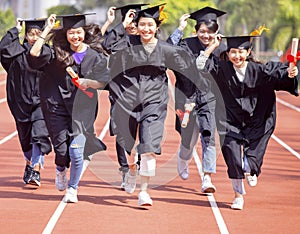 Happy graduation students  holding diploma and running on the stadium at school