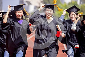 Happy graduation students  holding diploma and running on the stadium at school