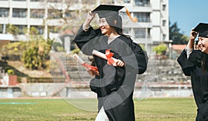 Happy graduation students  holding diploma and running on the stadium at school