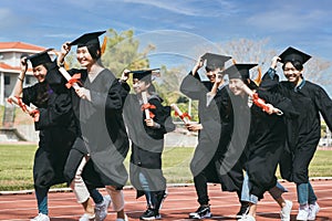 Happy graduation students  holding diploma and running on the stadium at school