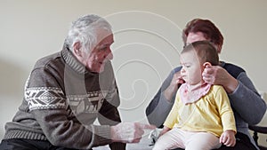Happy grand grandparents playing with a little toddler fussy at home 4k