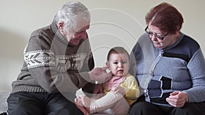 Happy grand grandparents playing with a little toddler fussy at home 4k