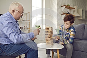 Happy granddad and his little grandson playing jenga and enjoying fun time together