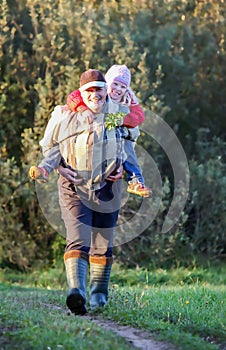 Happy grandfather carries a child on his back.