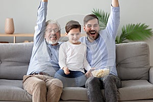 Happy grandfather, father and little son watching tv together