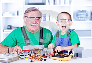 Happy grandfather and grandchild working in workshop