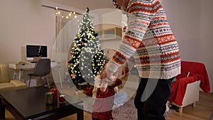 Happy grandfather and grandson are dancing near the Christmas tree. A large family is celebrating Christmas Eve at home