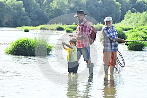 Happy grandfather and grandson are fishing on the river. Father, son and grandfather on fishing trip. Man with his son