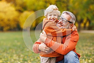 Happy   grandfather and grandson hug on autumn walk in park