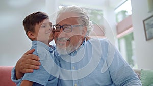 Happy grandfather and grandson hugging together in living room