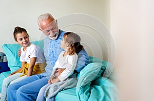 Happy grandfather and his grandchildren laughing and enjoying leisure time together.