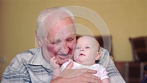 Happy grandfather holds a baby on hands and talking,play