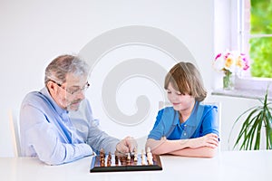 Happy grandfather playing chess with his grandson
