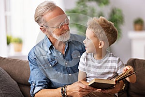 Happy grandfather reading book to grandson