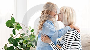 Happy grandma and granddaughter touching noses at home