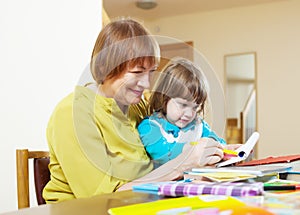 Happy grandmother and child drawing with pencils