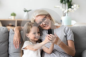 Happy grandmother and cute granddaughter using cellphone making