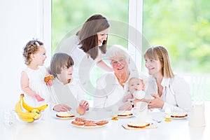 Happy grandmother enjoying breakfast with her family