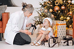 Happy grandmother giving christmas present to excited granddaughter.