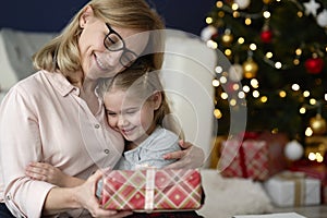 Happy grandmother giving her granddaughter a Christmas gift