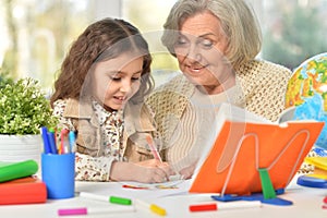 Happy Grandmother with granddaughter drawing together