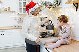 Happy grandmother and granddaughter drinking tea in christmas kitchen