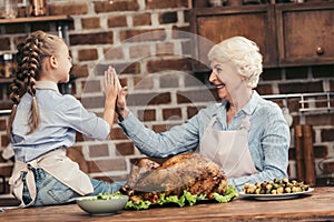 happy grandmother and granddaughter giving high five on thanksgiving after successful